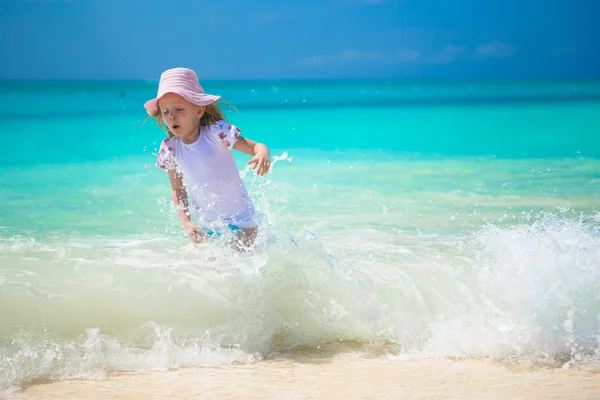 Niña feliz jugando en aguas poco profundas en la playa exótica —  Fotos de Stock