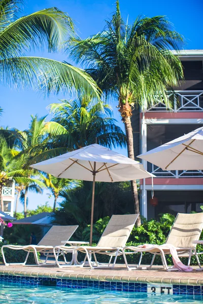 Sedie da spiaggia e ombrelloni vicino alla piscina in un hotel di lusso — Foto Stock