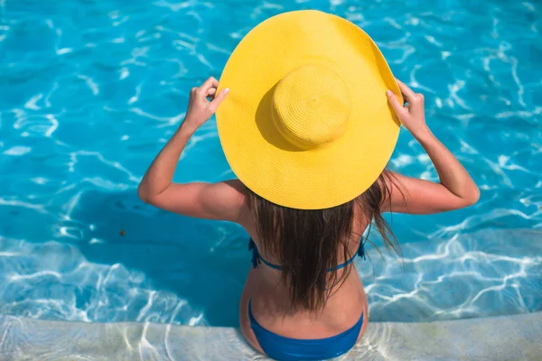 Mladá žena v žlutém klobouku relaxační u bazénu — Stock fotografie