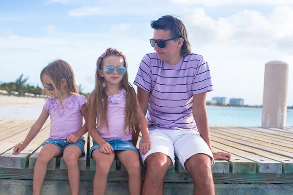 Famiglia di tre persone seduta su un molo di legno con vista sull'oceano — Foto Stock