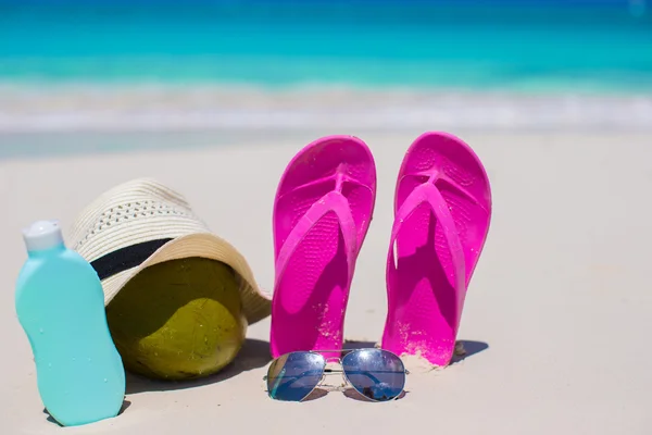 Flip flops, coconut, hat and suncream on white sand — Stock Photo, Image