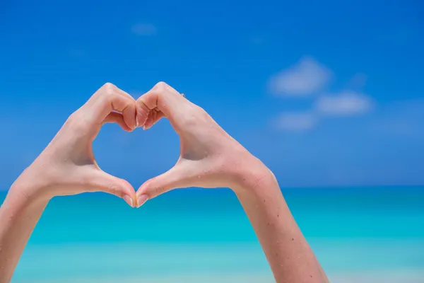 Closeup of heart made by hands background turquoise water — Stock Photo, Image
