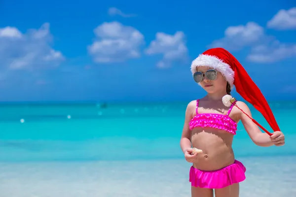 Маленькая очаровательная девочка в красном Санта-Клаусе наслаждается пляжным отдыхом — стоковое фото