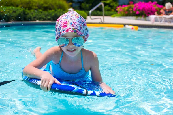 Bambina che nuota su una tavola da surf in piscina — Foto Stock