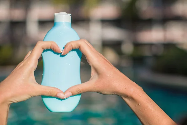 Close up of sunblock in female hands making heart — Stock Photo, Image