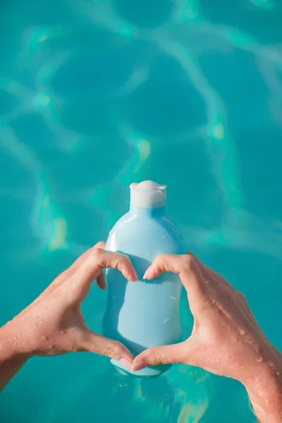 Closeup of sunblock in female hands bacjground the pool — Stock Photo, Image