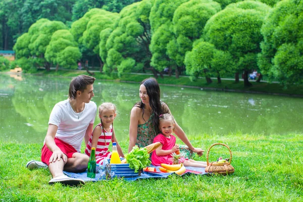 Young family on a picnic by the lake in park — Stock Photo, Image