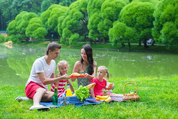 Happy young family picnicking outdoors — Stock Photo, Image