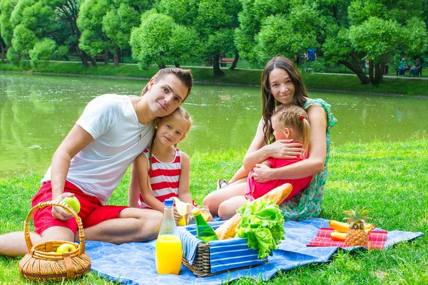 Familia joven feliz picnic al aire libre cerca del lago —  Fotos de Stock