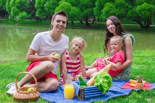 Familia joven feliz picnic al aire libre cerca del lago —  Fotos de Stock