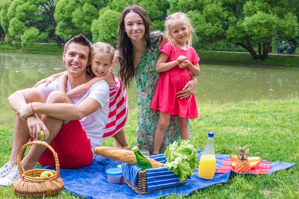 Glückliche niedliche vierköpfige Familie picknickt im Freien — Stockfoto