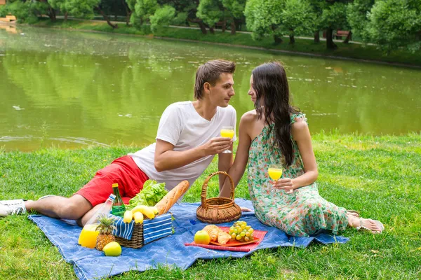 Jovem casal feliz piquenique ao ar livre perto do lago — Fotografia de Stock