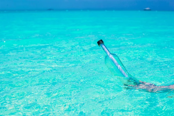 Flasche mit einer Botschaft in der Hand Hintergrund blauer Himmel — Stockfoto