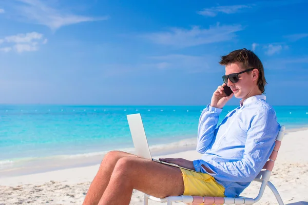 Giovane uomo d'affari che utilizza il computer portatile sulla spiaggia tropicale — Foto Stock