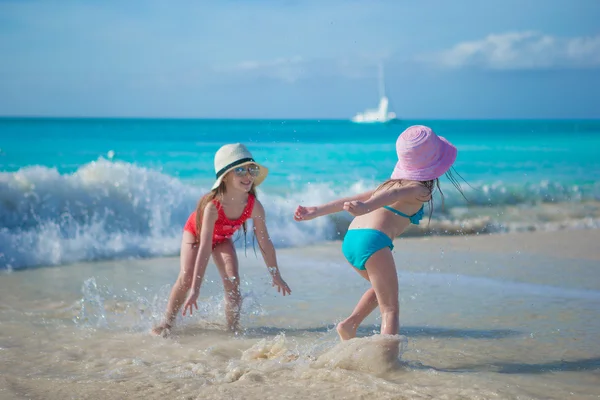 Adorables niñas jugando en aguas poco profundas en la playa exótica —  Fotos de Stock