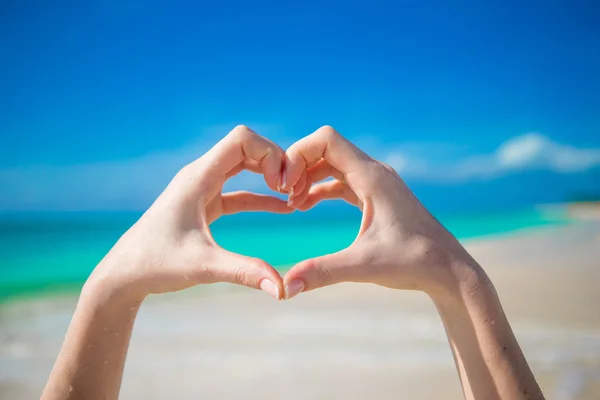 Close up of heart made by female hands background the turquoise ocean — Stock Photo, Image