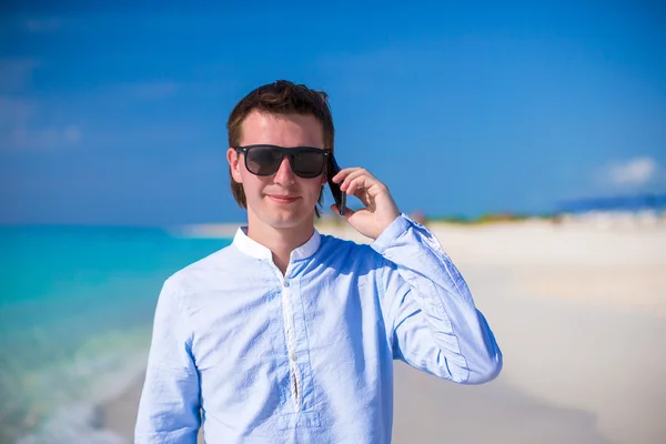 Giovane uomo con laptop e telefono sullo sfondo dell'oceano turchese sulla spiaggia tropicale — Foto Stock