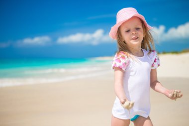 menina bonitinha jogando em águas rasas na praia exótica