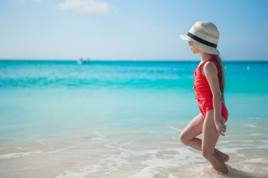 menina bonitinha jogando em águas rasas na praia exótica