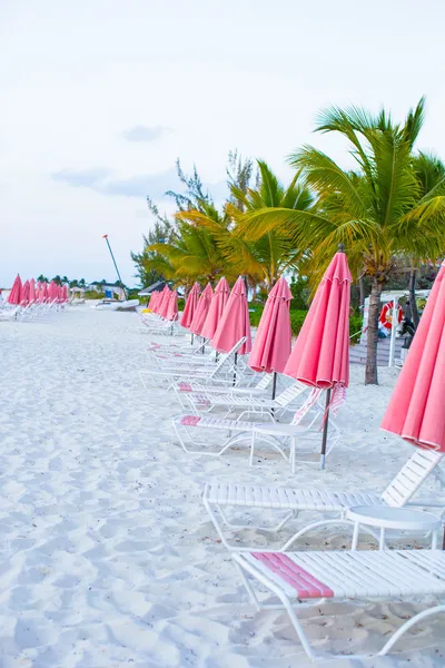 Парадоксальный вид на пустынный песчаный пляж с зонтиками и пляжным шезлонгом — стоковое фото