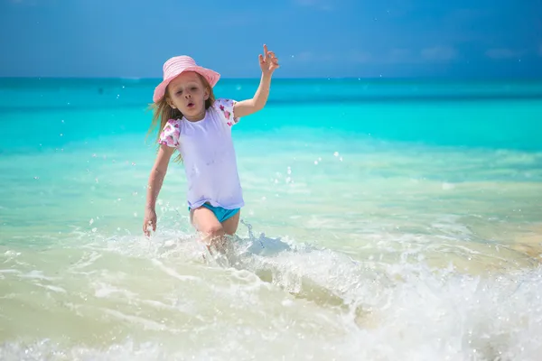 Petite fille mignonne courant en eau peu profonde à la plage exotique — Photo