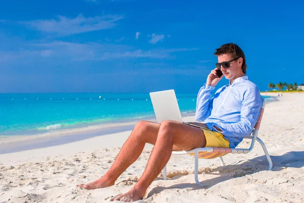 Młody biznesmen korzysta z laptopa na tropikalnej plaży — Zdjęcie stockowe