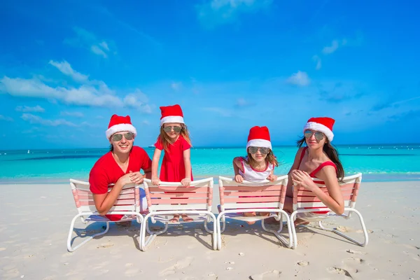 在圣诞老人的帽子在地处热带的海滩上尽情的家庭 — 图库照片