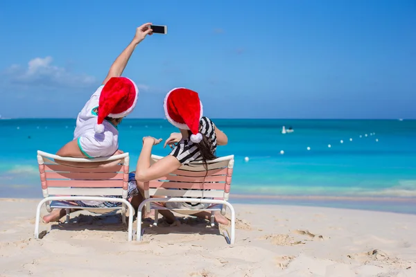 Giovane coppia felice in rosso Santa cappelli scattare una foto — Foto Stock