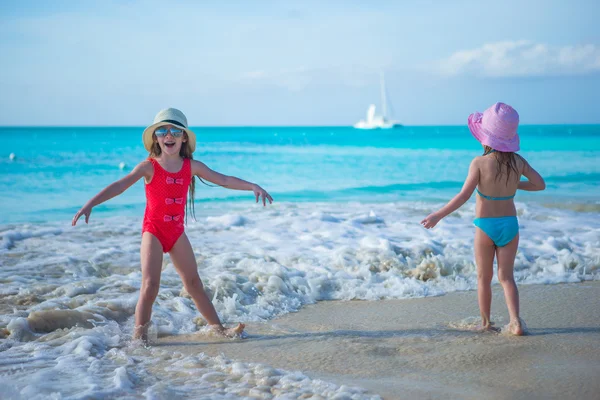 Bedårande små flickor som spelar i grunt vatten vid tropiska vita stranden — Stockfoto