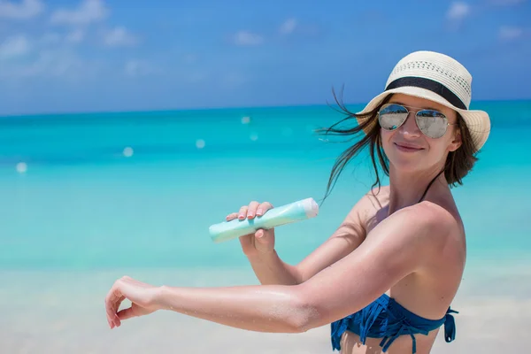 Glimlachend jonge vrouw die van toepassing zijn zonnebrandcrème op strand — Stockfoto