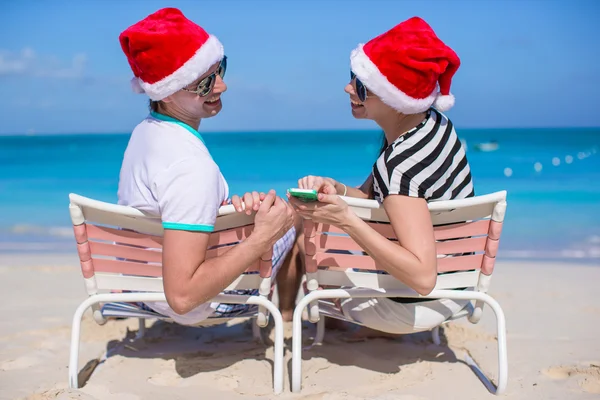 Mladý pár v santa klobouky Užijte si dovolenou na pláži — Stock fotografie