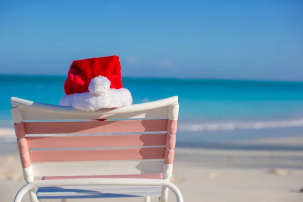 关闭了圣诞老人的帽子在椅子上贵妃在地处热带的海滩上 — 图库照片