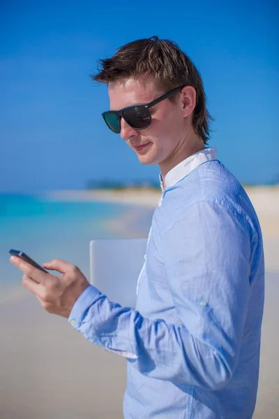 Affärsman med telefonen i handen på en tropisk strand — Stockfoto