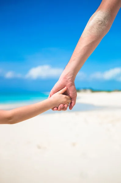 Close up of father and little kid holding each other hands at beach — Stock Photo, Image