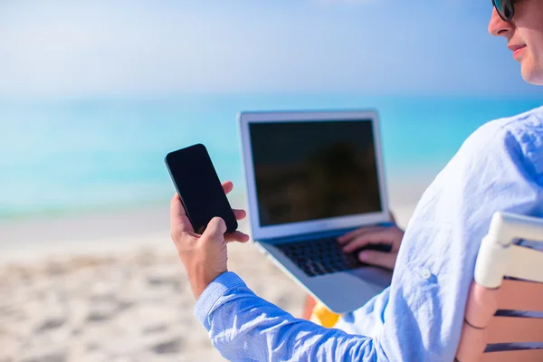 Primer plano de teléfono en el fondo de la computadora en la playa — Foto de Stock