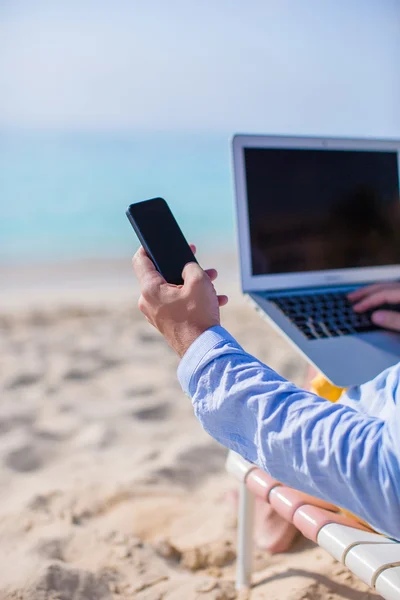 Primer plano de teléfono en el fondo de la computadora en la playa —  Fotos de Stock