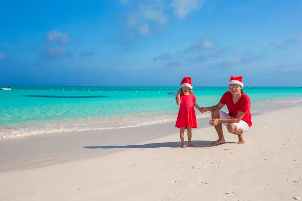 小女孩，在圣诞老人的帽子在异国海滩的快乐老爸 — 图库照片