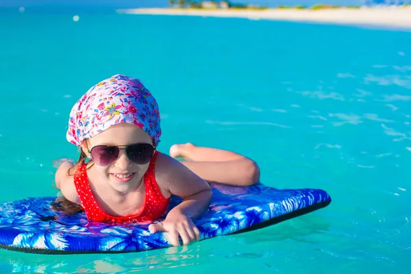 Little adorable girl on a surfboard in the turquoise sea — Stock Photo, Image