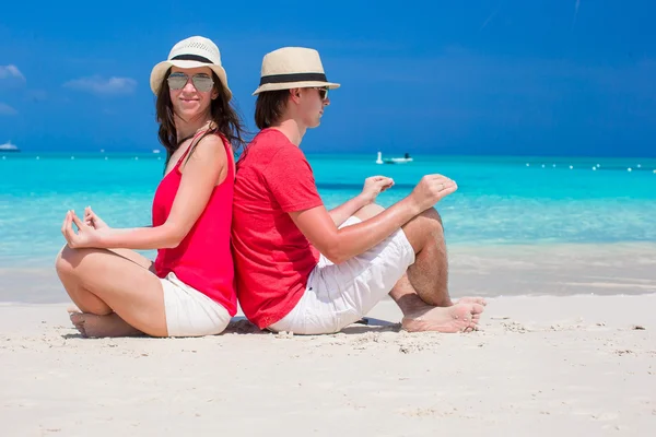 Happy lovely couple in lotus position on tropical white beach — Stock Photo, Image