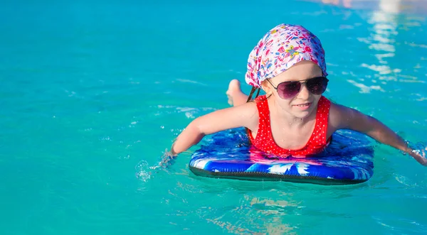 Menina adorável em uma prancha de surf no mar azul-turquesa — Fotografia de Stock