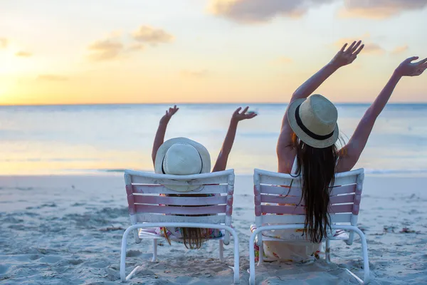 Holčička a matka sedí na židlích, pláž při západu slunce — Stock fotografie