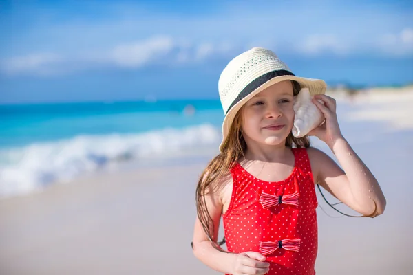Little cute girl with seashell in hands at tropical beach — Stock Photo, Image