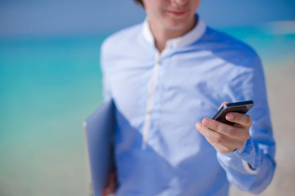 Zblízka v mužské ruce na tropické pláži telefon — Stock fotografie