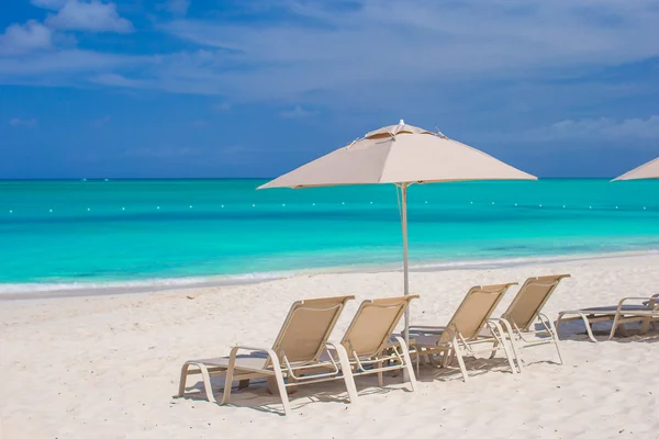 Vita parasoller och solstolar på tropical beach — Stockfoto