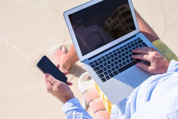 Primer plano de teléfono en el fondo de la computadora en la playa —  Fotos de Stock