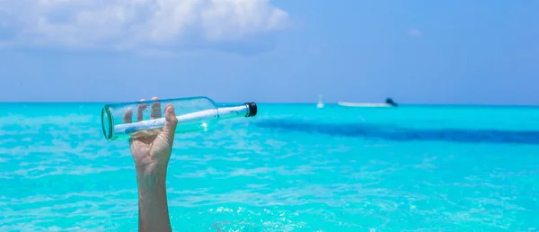 Flasche mit einer Botschaft in der Hand Hintergrund blauer Himmel — Stockfoto