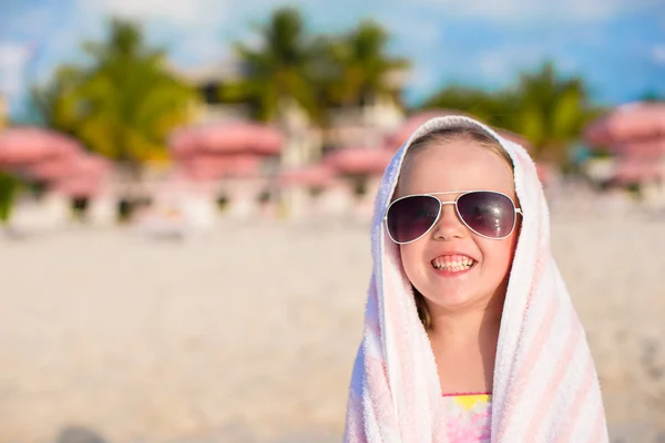 Niña adorable en gafas de sol cubiertas con toalla en la playa tropical —  Fotos de Stock