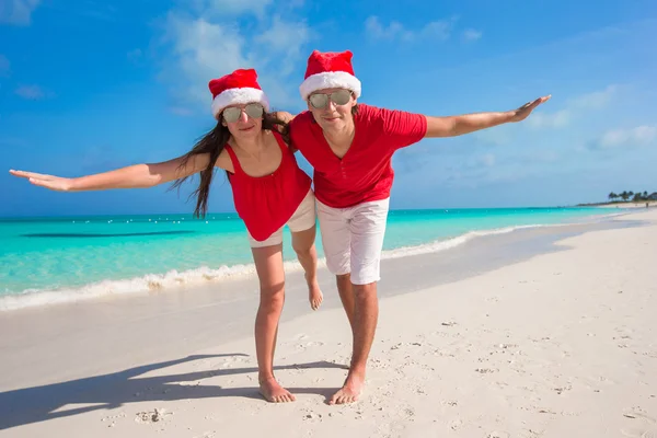 Casal bonito em chapéus de Santa na praia tropical se divertir — Fotografia de Stock