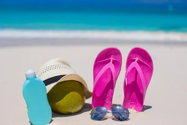 Flip flops, coconut and suncream on white sand — Stock Photo, Image