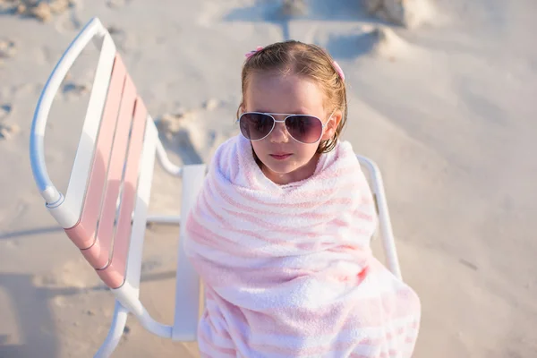 Adorable petite fille dans des lunettes de soleil couvertes de serviette à la plage tropicale — Photo